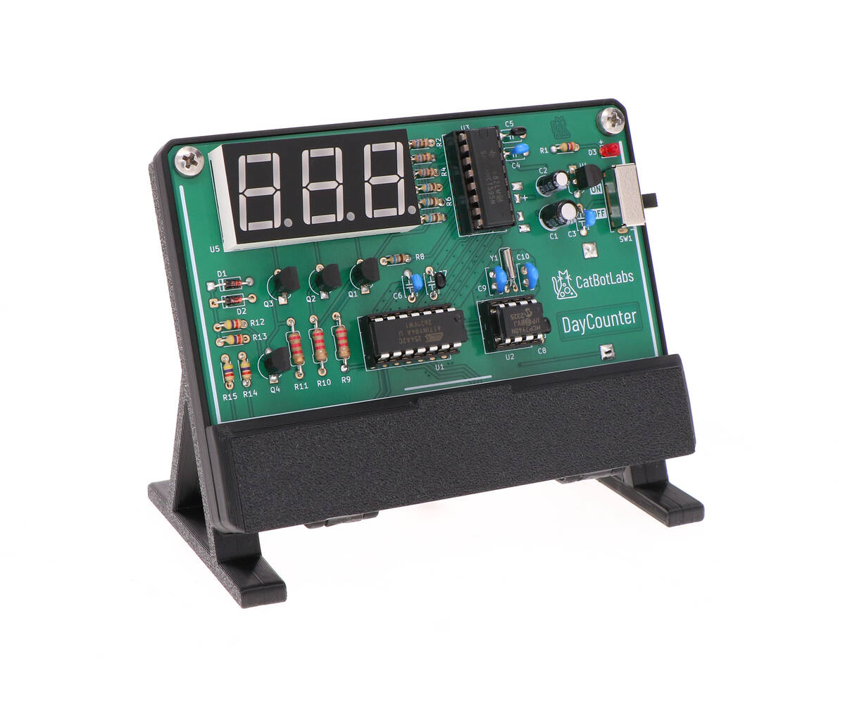 The assembled DayCounter circuit board, with a 3-digit 7-segment display in the upper-left, on a black plastic display stand.